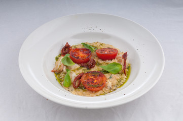 seafood risotto and dried tomatoes on a white plate on a white background