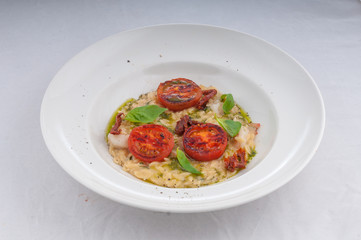 seafood risotto and dried tomatoes on a white plate on a white background