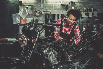 African american woman mechanic repairing a motorcycle in a workshop © Nejron Photo