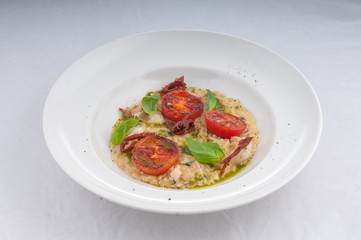 seafood risotto and dried tomatoes on a white plate on a white background