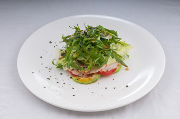 salad with rucola and vegetables zucchini tomatoes on a white plate on a clean white background