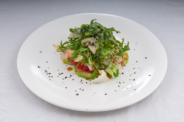 salad with rucola and vegetables zucchini tomatoes on a white plate on a clean white background
