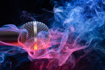 microphone enveloped in multicolored smoke on black gìbackground