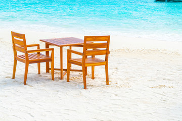 wood table and chair on beach with sea view background in Maldives