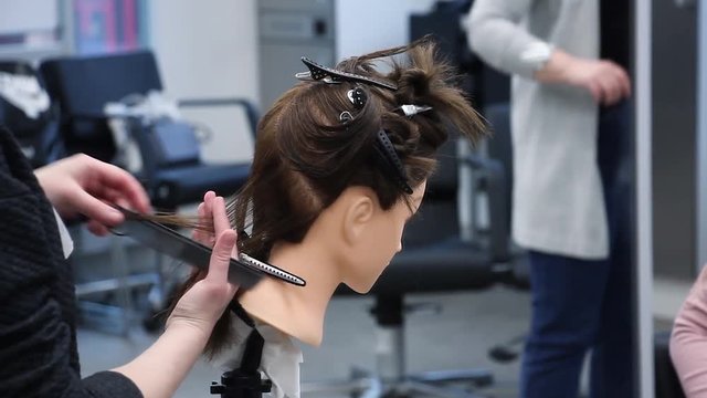 beginner hairdresser practices new skills on a mannequin head, simulates hair cutting with scissors, training at hairdressing workshop, learning new profession or refresher course