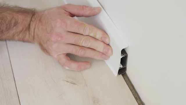 Finishing work at home - The master mounts and installs the baseboard to the wall