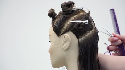 hairdresser carefully combs and make hair parting on dummy head,  practices new skills and training at hairdressing workshop, learning new profession or refresher course, side view close-up