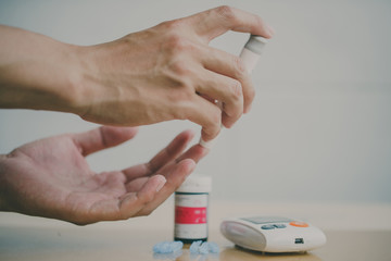 Close up of woman hands using lancet on finger to check blood sugar level by Glucose meter using as Medicine, diabetes, glycemia, health care and people concept.