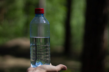 hand holding water bottle on garden background