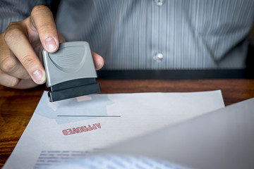 Hands of businessman stamp on paper document to approve business investment contract agreement