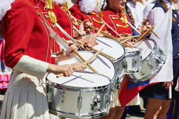 A group of girls in red uniforms playing on white front drums