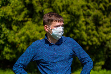 a man in a mask from allergy, in a blue shirt, stands in the park
