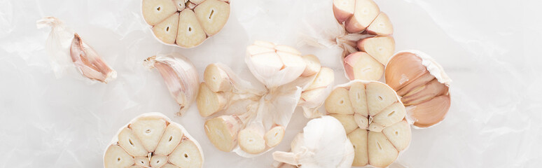 panoramic shot of cut garlic cloves on white paper background