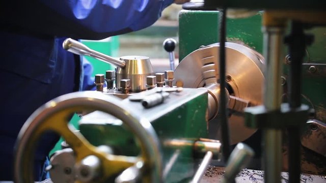 A man turns off the lathe and measures the diameter of the rod.