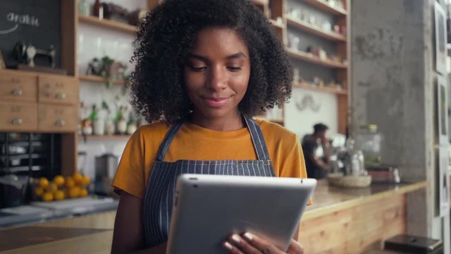 A smiling female cafe owner using digital tablet