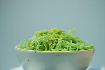 Green noodle in white ceramic bowl