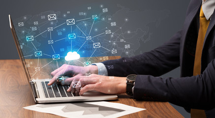 Businessman hand sending a bunch of messages on laptop with cloud computing concept
