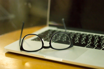 glasses and laptop top view on wooden desk. Lifestyle workspace, top view.