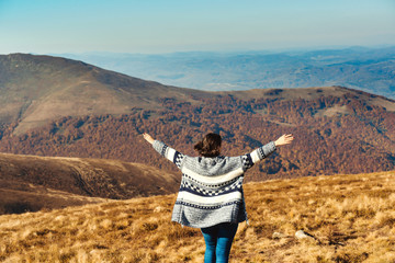 Happy freedom girl in mountains. Woman rising hands on top of autumn mountain. Travel, freedom and...