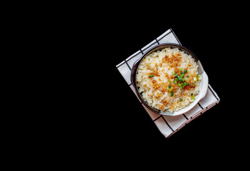 Garlic fried rice in ceramic plate with wood spoon on black background.