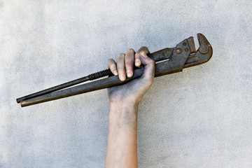 Hand holding a adjustable wrench isolated on gray background.