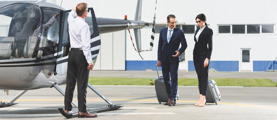panoramic shot of business partners with luggage near pilot and helicopter © LIGHTFIELD STUDIOS