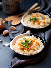 Garlic fried rice in ceramic plate with wood spoon on black background.