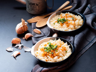 Garlic fried rice in ceramic plate with wood spoon on black background.