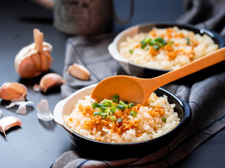 Garlic fried rice in ceramic plate with wood spoon on black background.