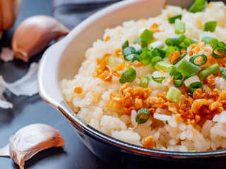 Garlic fried rice in ceramic plate with wood spoon on black background.