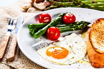 Fried egg with vegetables and toast on wooden table