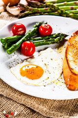 Fried egg with vegetables and toast on wooden table