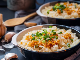 Garlic fried rice in ceramic plate with wood spoon on black background.