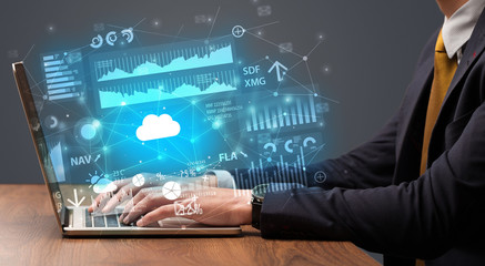 Businessman hand typing on laptop with reports and graphs concept around
