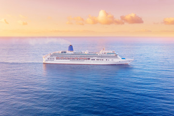 White cruise liner floats across blue sea into sunset. Concept travel. Aerial view