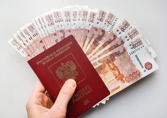 Russian money and passport on a gray background, close-up, passport and money fan in hand