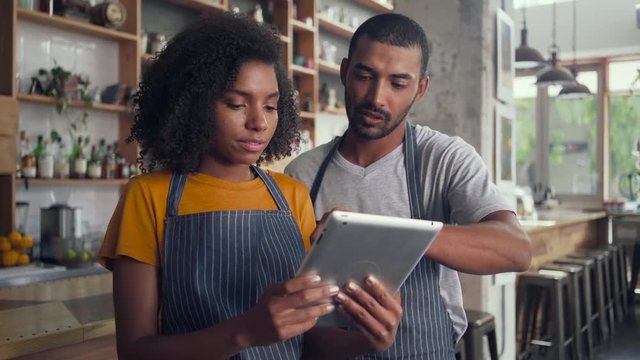 Smiling cafe owner in apron looking at digital tablet