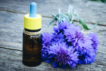 cornflower essential oil on a wooden background.