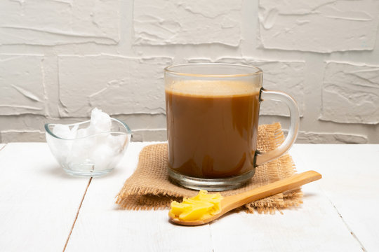 Bulletproof coffee with ghee oil and coconut oil on white wooden background. Image with copy space.