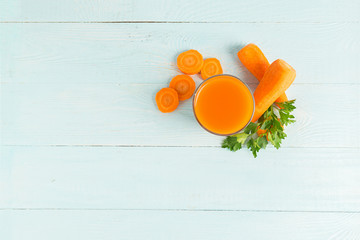 A glass of fresh carrot juice on a wooden blue background. Copy space. Flat Layout Top View