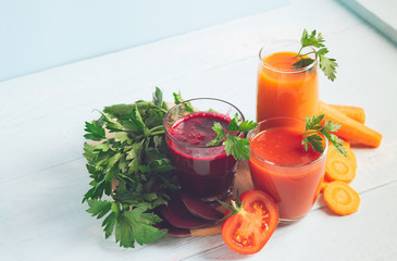 Fresh juice smoothies from a variety of vegetables beetroot apple carrot tomatoes in glasses on wooden blue background.