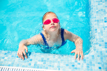 Happy little girl in goggles playing in swimming pool Beach resort, summer vacation, travel and tourism concept Relax