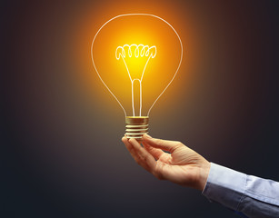 Hand holding light bulb on dark background, new idea concept