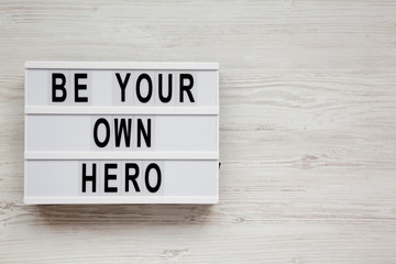 'Be your own hero' words on a modern board over white wooden background, top view. Flat lay, overhead, from above. Copy space.