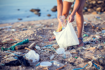 Woman collect garbage on the beach. Environmental pollution concept