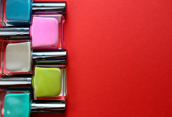 Texture multicolored bottles with varnish lie on a red background