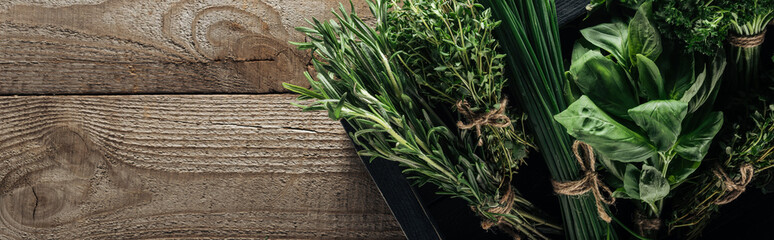 panoramic shot of green thyme, spinach, rosemary and green onion in box on wooden weathered table...
