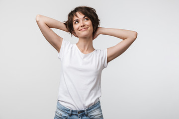 Image of optimistic woman in basic t-shirt touching her hair and looking aside