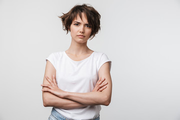 Portrait of serious woman with short brown hair in basic t-shirt frowning and looking at camera