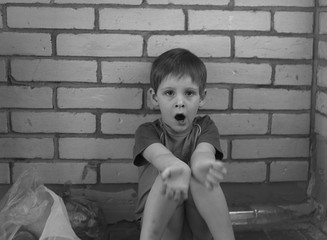 Dramatic portrait of kid looking at camera with angry face, Emotional photo of Displeased boy with unhappy face, Head shot of anger young caucasian boy, Family violence concept.Black and white photo